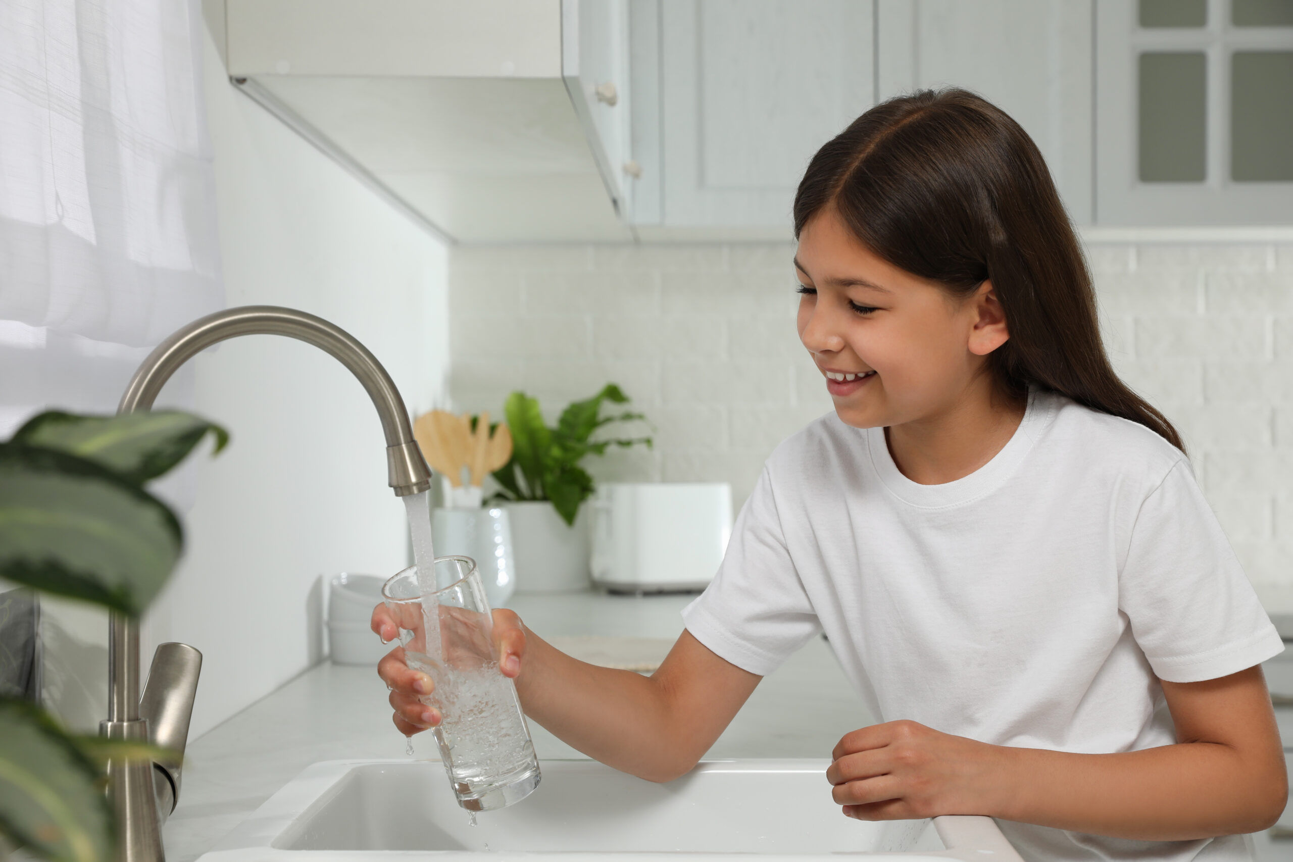 Girl filling glass with water from tap in kitchen Girl filling glass with water from tap in kitchen
